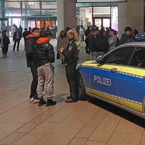 Eine Polizistin befragt zwei junge Männe vor der Europa Passage.