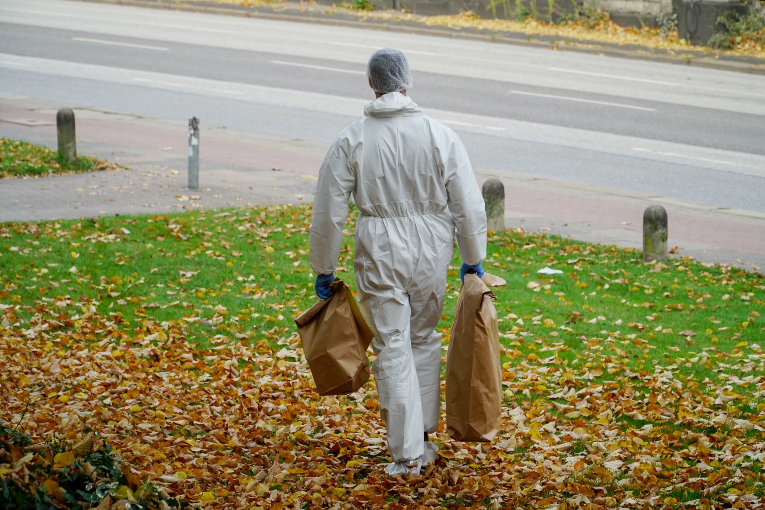 Ein Beamter der Spurensicherung; er trägt einen weißen Overall, in den Händen Tüten mit gesicherten Spuren (Symbolfoto)