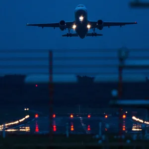 Ein nächtlicher Start am Hamburger Flughafen. Im Hintergrund setzt ein Flugzeug zur Landung an.