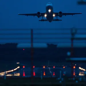 Ein nächtlicher Start am Hamburger Flughafen. Im Hintergrund setzt ein Flugzeug zur Landung an.