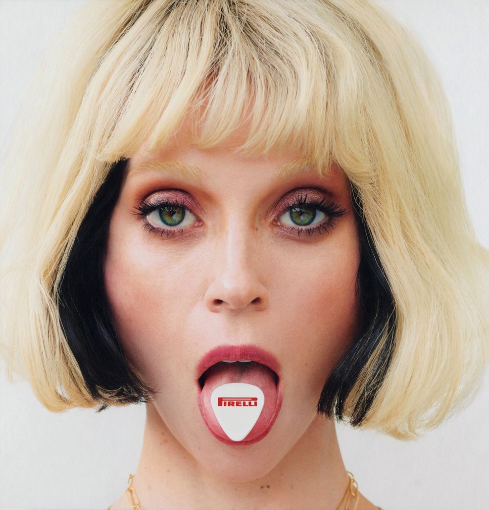 Porträt einer Frau, auf ihrer rausgestreckten Zunge steht Pirelli