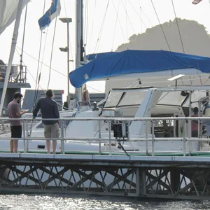 Männer stehen vor und auf einem Segelboot. einer der Männer trägt eine Warnweste
