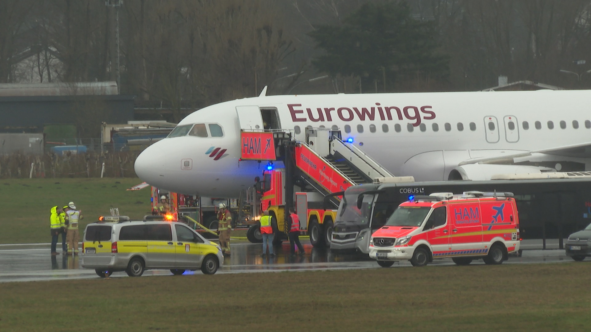 Helfer stehen auf dem Flughafengelände an einem Flugzeug. Zwei geplatzte Reifen an der Eurowings-Maschine haben am Hamburger Flughafen für einen Großeinsatz gesorgt.