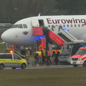 Helfer stehen auf dem Flughafengelände an einem Flugzeug. Zwei geplatzte Reifen an der Eurowings-Maschine haben am Hamburger Flughafen für einen Großeinsatz gesorgt.