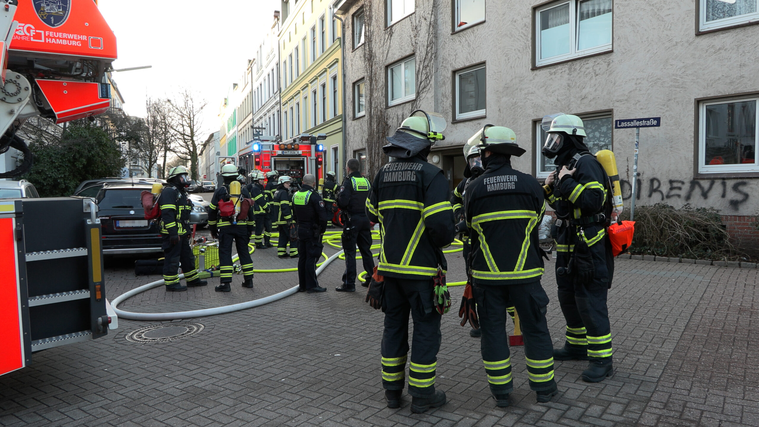 Einsatzkräfte der Feuerwehr vor dem Wohnhaus in der Lassallestraße in Hamburg-Harburg.