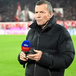 Lothar Matthäus steht mit seinem Handy und einem Sky-Mikrofon in der Hand auf dem Spielfeld.
