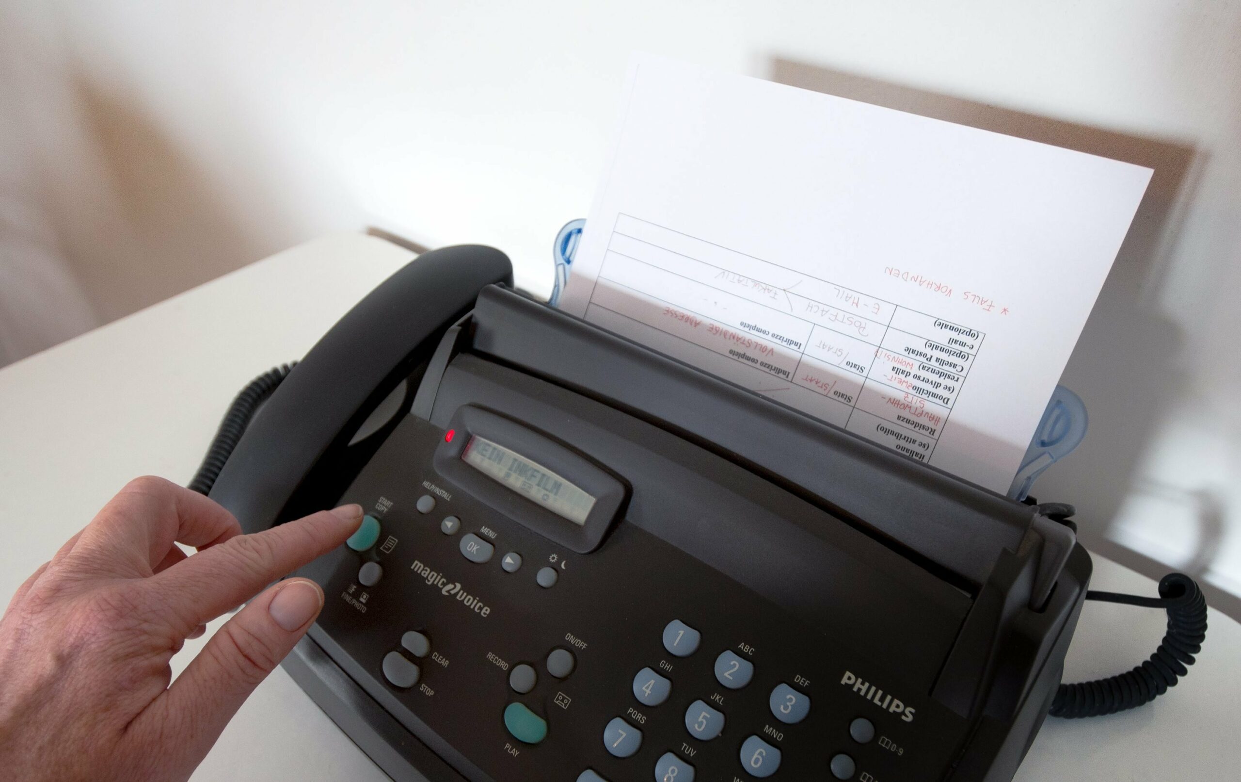 Eine Hand betätigt ein Faxgerät.
