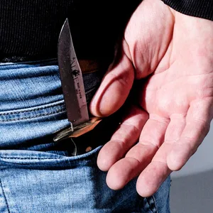 Ein Mann von hinten, in seiner Hosentasche steckt ein Messer (Symbolbild).