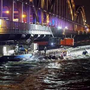 Im Dunklen ist ein Schiff unter einer Brücke. Das Schiff ist eigentlich zu hoch für die Brücke, deshalb der Unfall.
