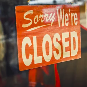 Schild mit der Aufschrift „Sorry we‘re closed“ hängt in einem Schaufenster,