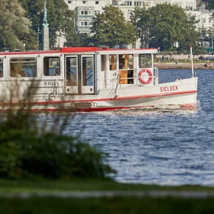 Die „Sielbek“, eines von 18 Schiffen der Alter Touristik, fährt bei sommerlichem Wetter auf der Alster (Archivbild).