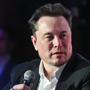 Elon Musk hält ein Mikrofon mit beiden Händen