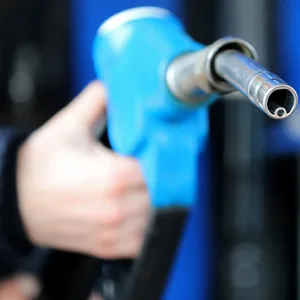 Ein Mann hält eine Zapfpistole an einer Tankstelle in seiner Hand.