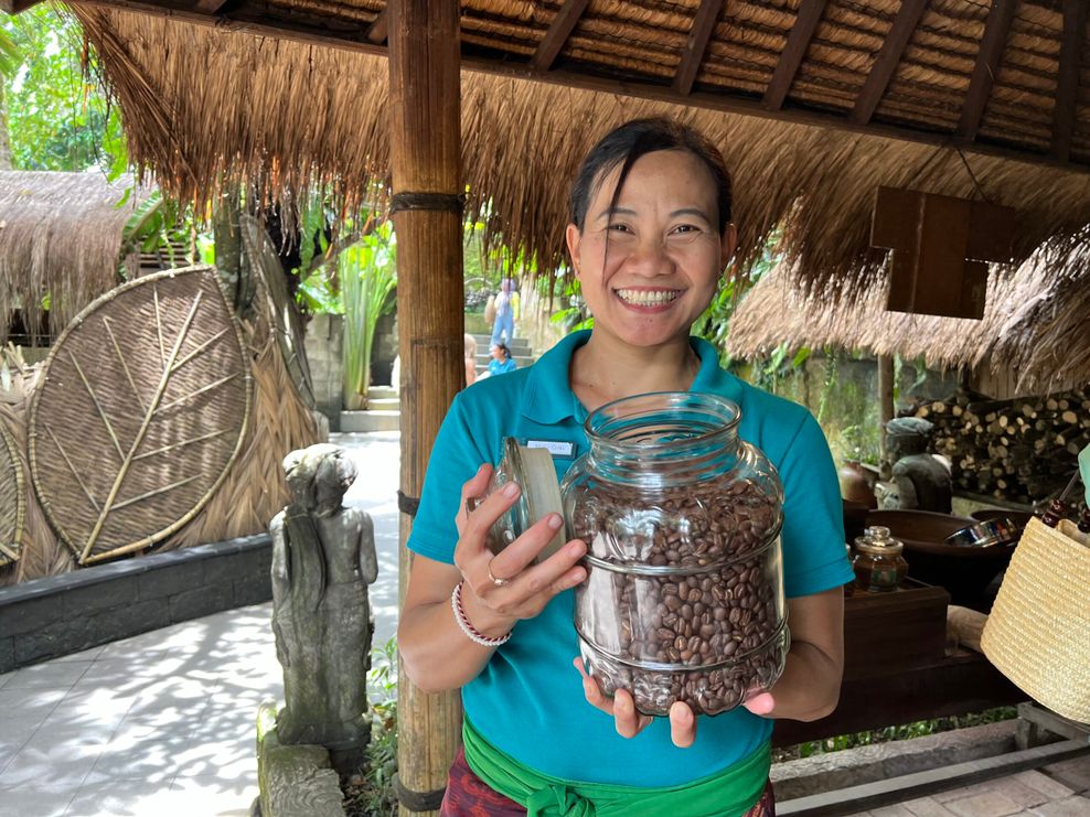 Eine Balinesin hält ein Glas mit Luwak Coffee