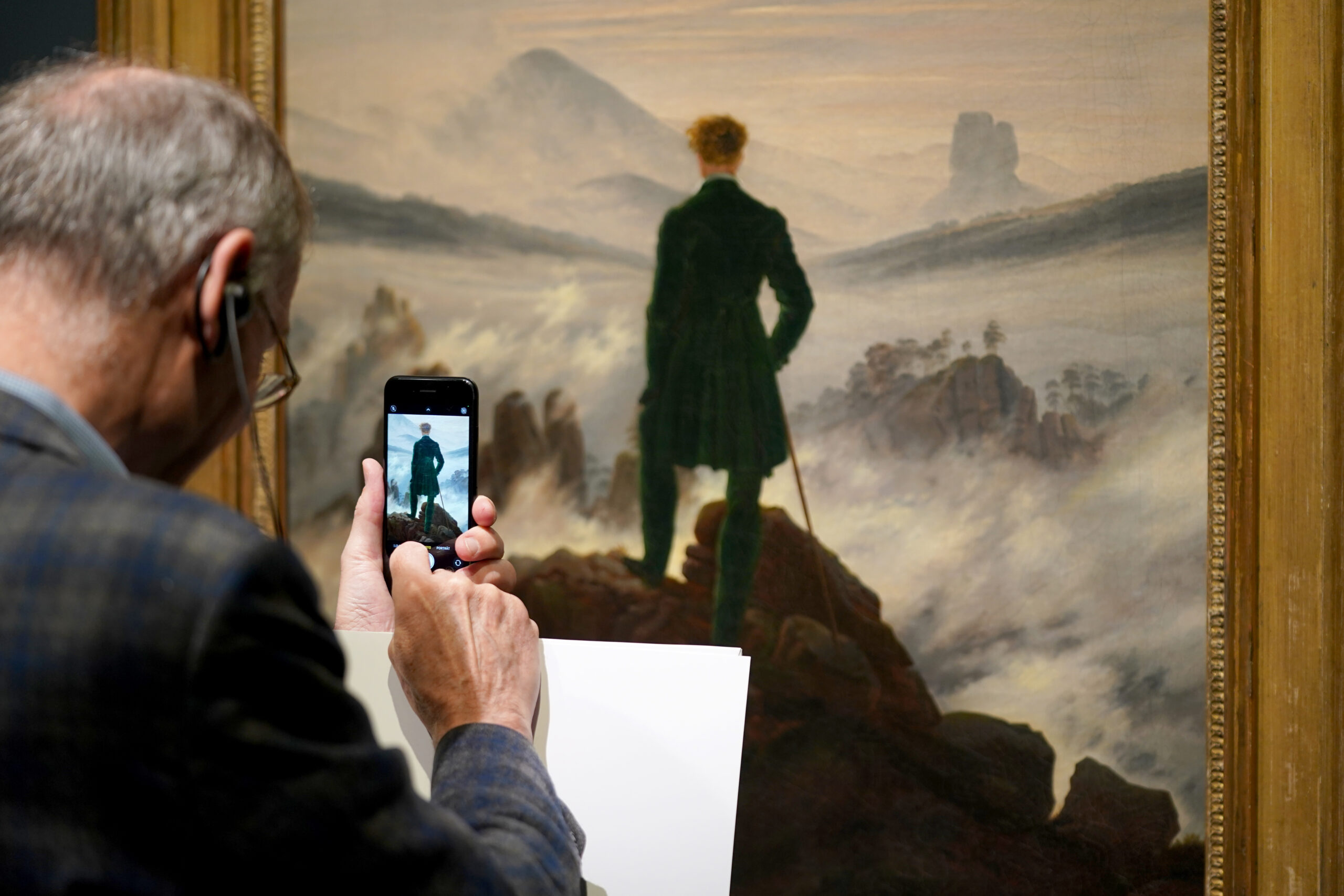 Ein Mann fotografiert das Gemälde „Der Wanderer über dem Nebelmeer“ von Caspar David Friedrich