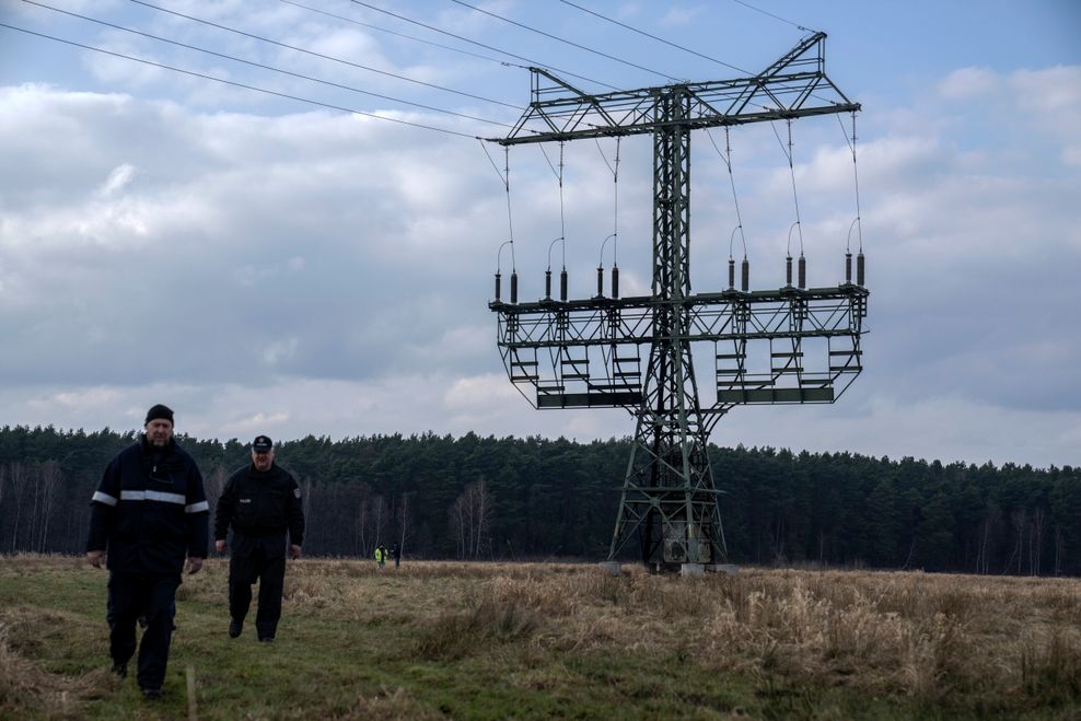 Polizisten neben dem beschädigten Strommast