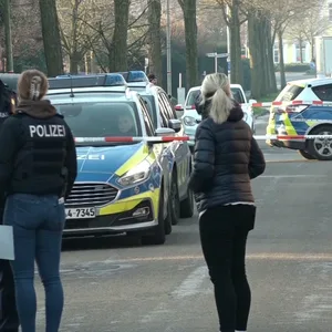 Straße mit Polizeibeamten, Polizeiwagen und Absperrband