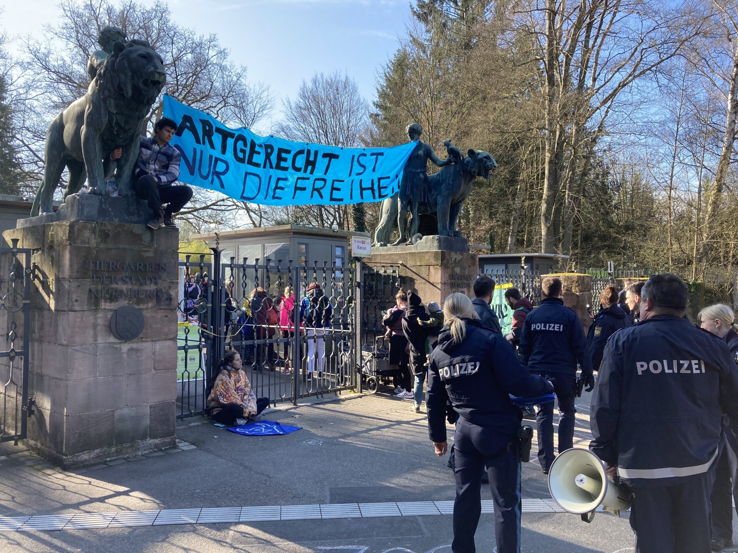 Aktivisten sitzen mit einem Plakat "Artgerecht ist nur die Freiheit" vor dem Eingang des Nürnberger Zoos