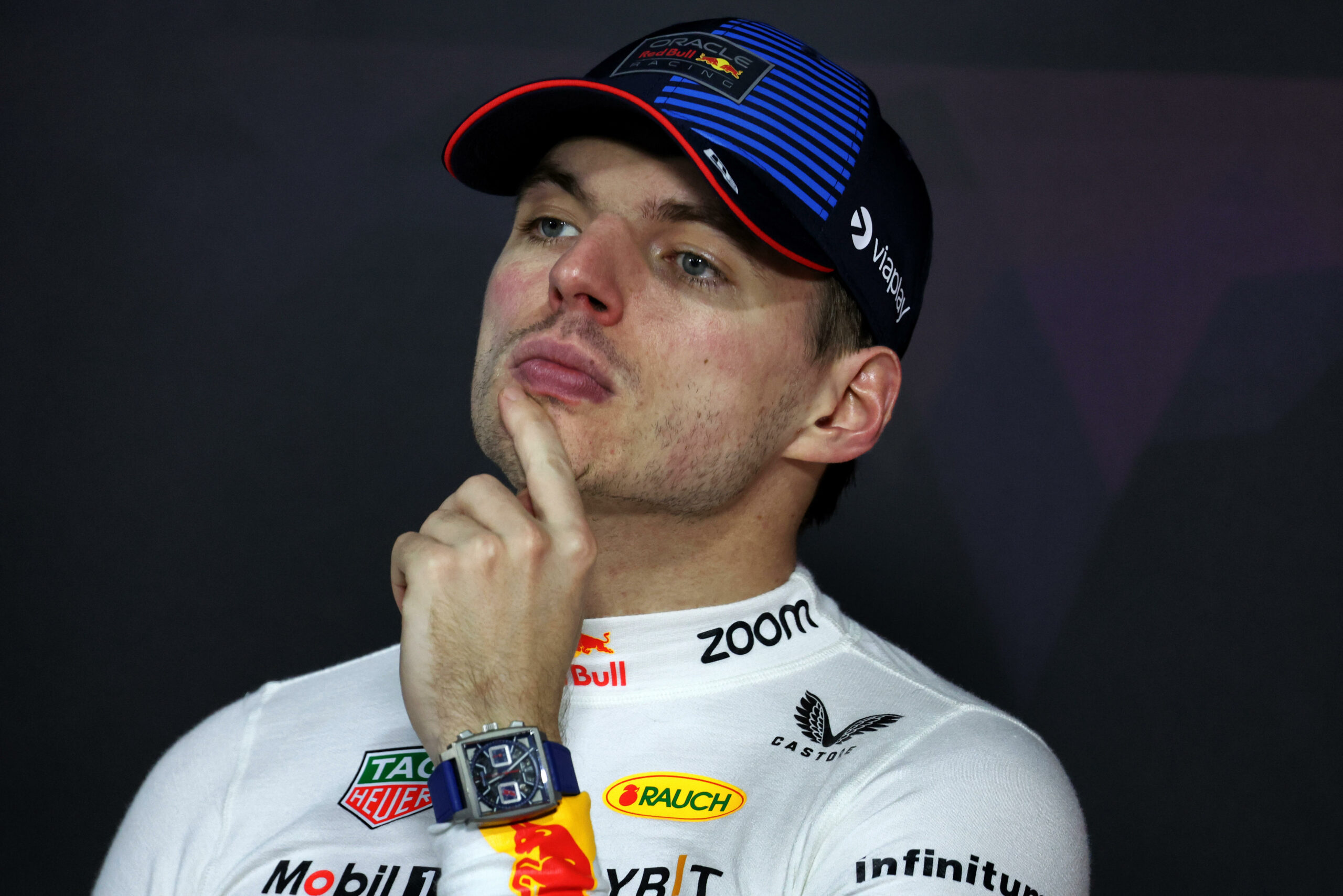 Max Verstappen fasst sich auf einer Pressekonferenz nachdenklich ans Kinn.