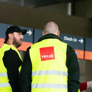 Drei Männer mit Verdi-Warnwesten stehen vor einem