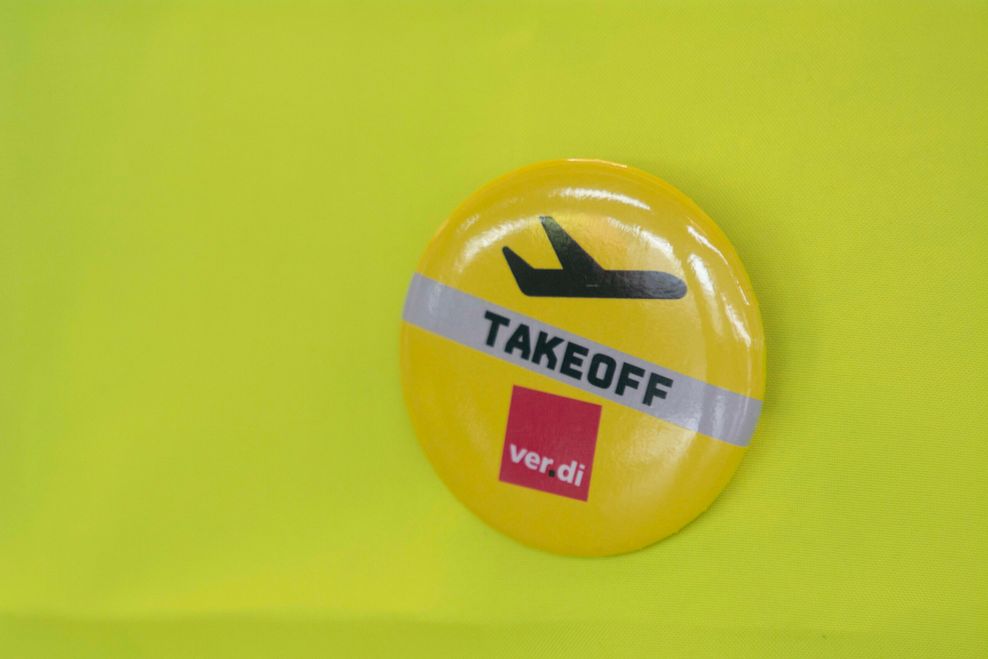 ein Button, auf dem Takeoff steht, ein abhebendes Flugzeug und das Verdi-Logo gezeigt wird.