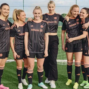Fünf Spielerinnen des FC Bayern München posieren in den neuen Trikots mit Designerin und Model Lena Gercke.