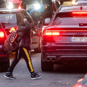 Autos und Kinder drängen sich vor Unterrichtsbeginn dicht an dicht vor einer Grundschule.