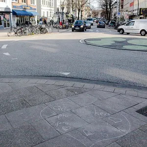 Auf dem Gehweg an dem Kreisel ist noch ein Kreideherz zu sehen, in dem undeutlich die Parolen "Querdenken", „Pro AfD“ und „Pro Rechtsextrem“ zu lesen sind.