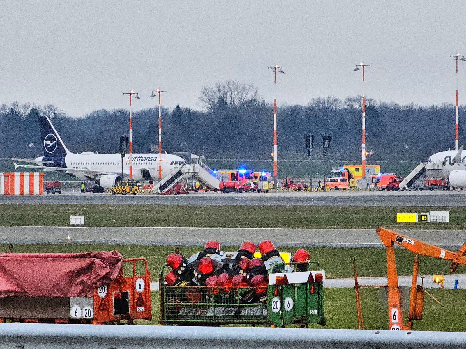 Am Flughafen ist ein der Distanz ein Flugzeug und mehrere Rettungswagen der Feuerwehr zu sehen