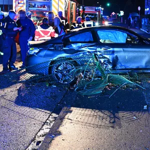 Polizisten begutachten den BMW und den Schaden, den der Fahrer verursachte.