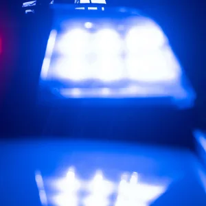 Polizisten stehen bei einem nächtlichem Einsatz vor ihrem Streifenwagen.