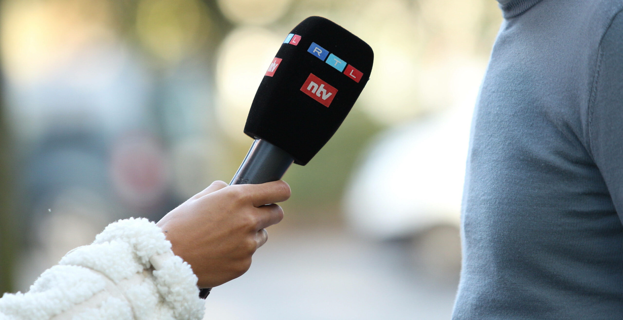 Frau hält ein Mirkofon mit dem Logos von RTL und NTV in der Hand