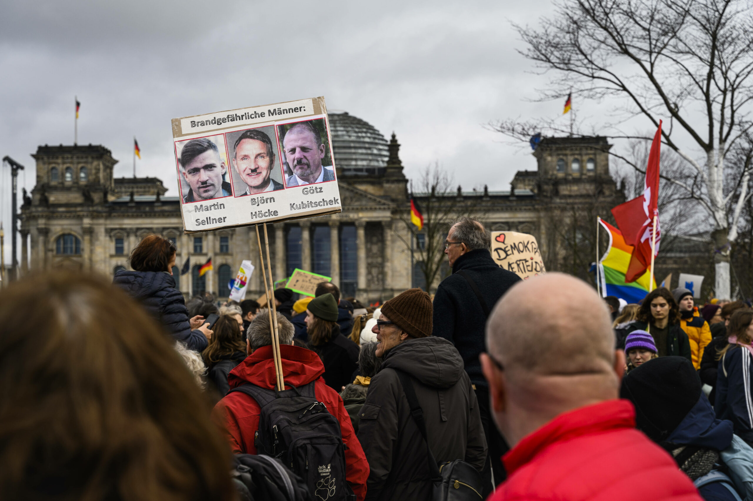 Auf einem Plakat bei einer Demo in Berlin sind die drei Rechtsextremisten Martin Sellner, Björn Höcke und Götz Kubitschek zu sehen, darüber steht „Brandgefährliche Männer“
