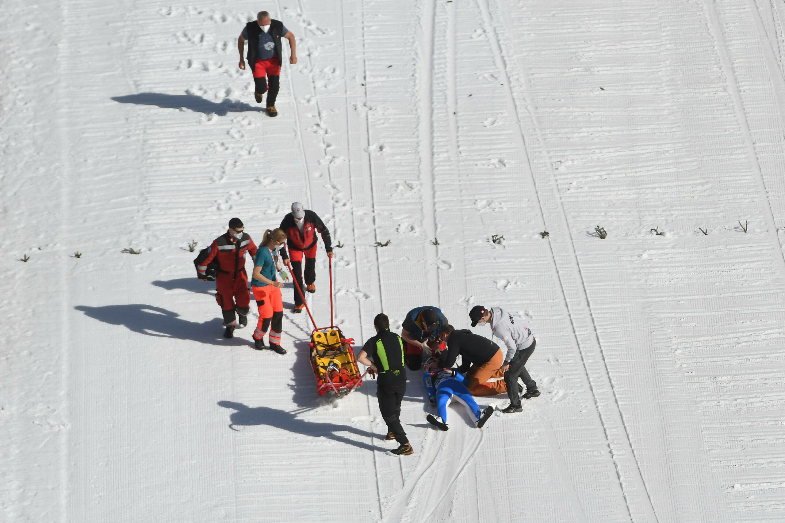 Sanitäter und Ersthelfer kümmern sich um einen gestürzten Skispringer.