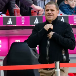 Max Eberl zieht vor der Bayern-Auswechselbank seine Jacke zu.