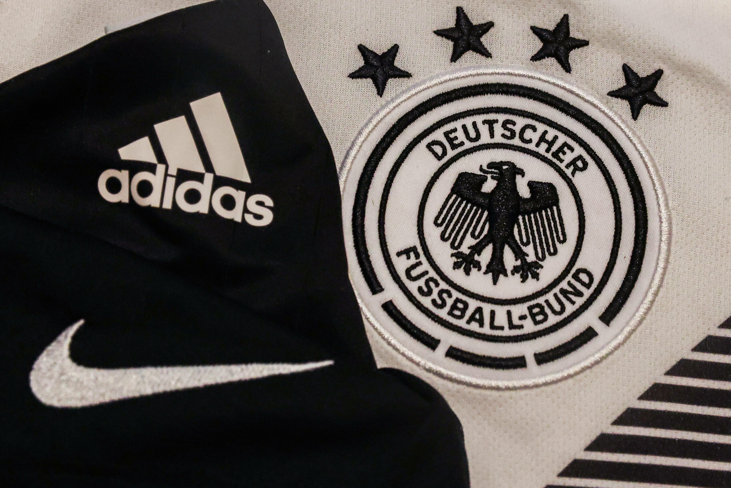 Ein Adidas-Logo, ein Nike-Logo und das Wappen des DFB.