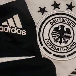 Ein Adidas-Logo, ein Nike-Logo und das Wappen des DFB.