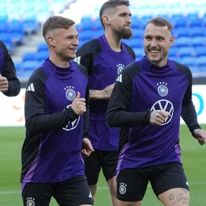Joshua Kimmich läuft lachend mit seinen Teamkollegen auf dem Trainingsplatz.