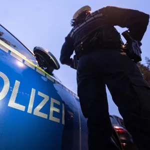 Eine Polizistin steht neben einem Polizeifahrzeug. (Symbolbild)