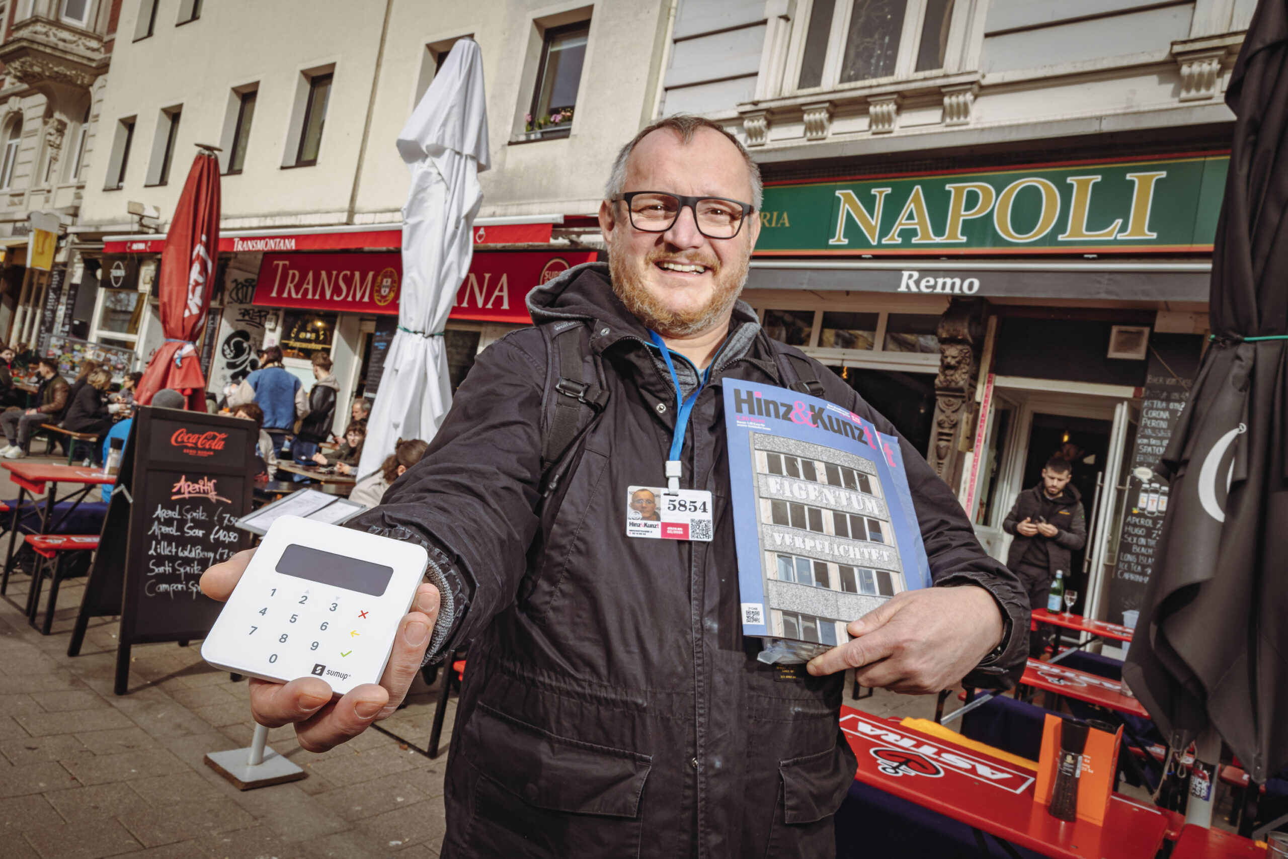 „Hinz&Kunzt“-Verkäufer Thomas mit seinem Kartenlesegerät und einigen Zeitschriften