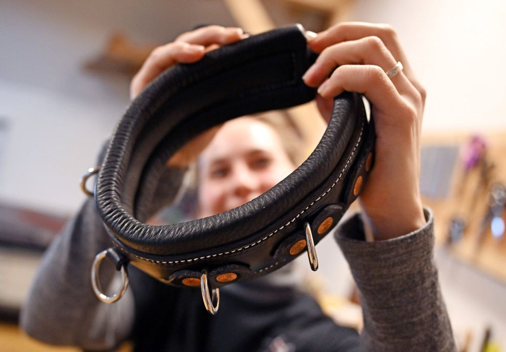 Die Sattlerin Viktoria Kottler arbeitet in ihrer Werkstatt an einem Lederhalsband.