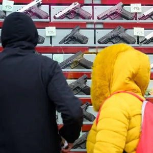 Passanten vor dem Schaufenster eines Waffengeschäfts, das Schreckschuss- und Signalwaffen verkauft (Symbolbild)
