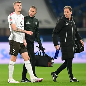Eric Smith geht mit St-Paulis Physiotherapeut und Mannschaftsarzt vom Platz.