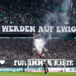 Die Fans von Werder Bremen halten zwei Banner hoch.