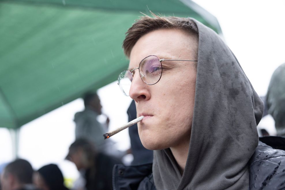 Junger Mann mit Kapuze raucht einen Joint