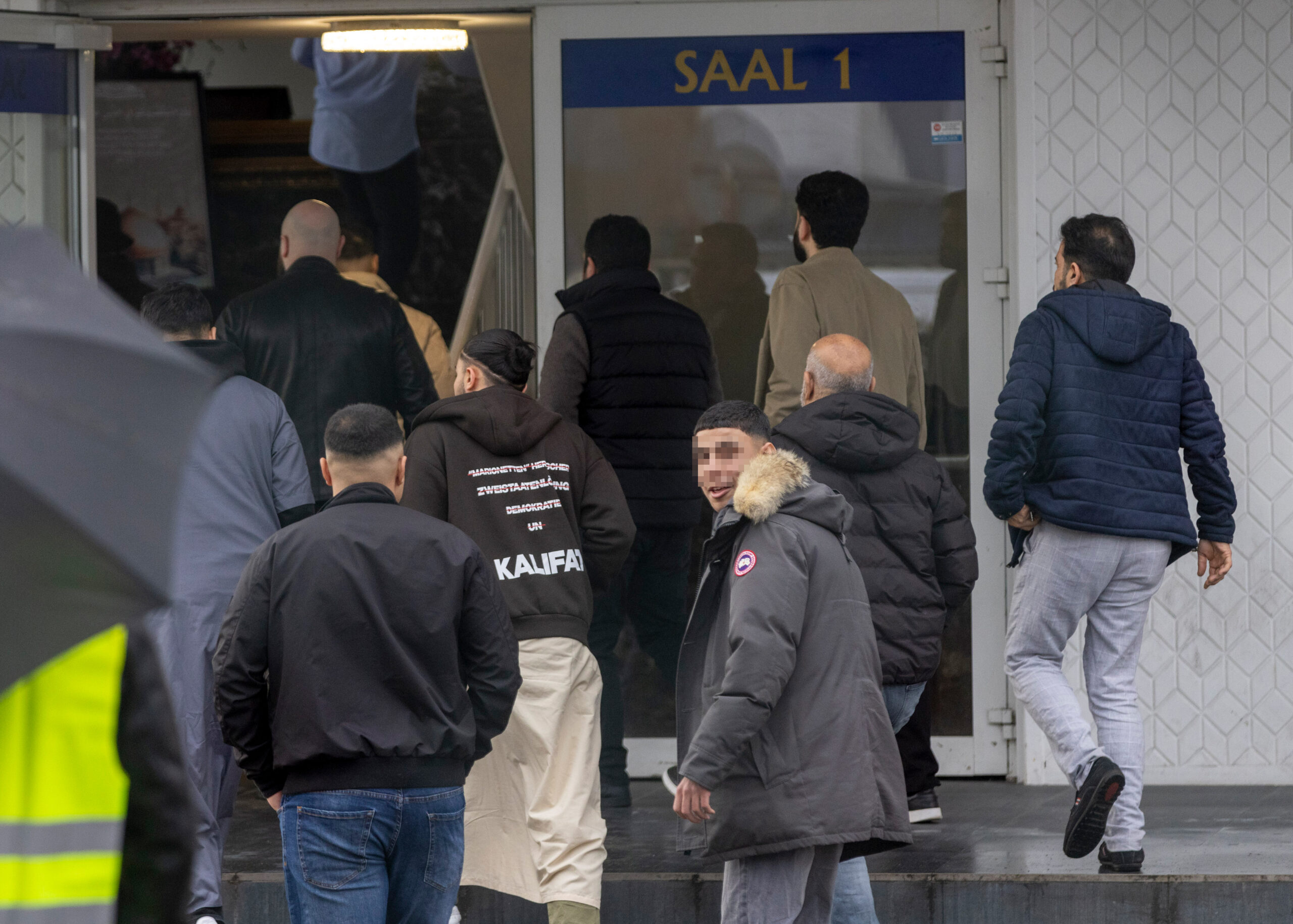 Männliche Islamisten betreten eine Halle.