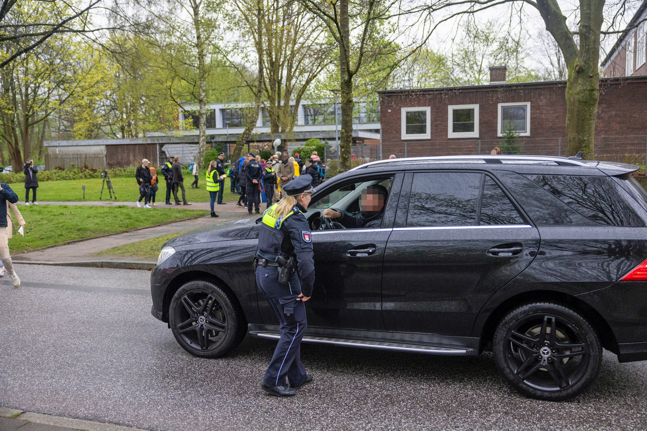 Eine Polizistin im Gespräch mit einem Vater, der sein Kind mit einem Mercedes-SUV bis vor die Schule gefahren hatte.