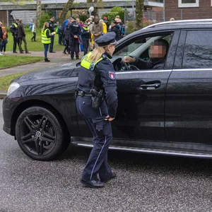 Eine Polizistin im Gespräch mit einem Vater, der sein Kind mit einem Mercedes-SUV bis vor die Schule gefahren hatte.