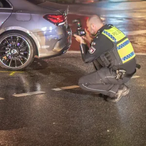 Ein Polizist fotografiert den beschädigten Mercedes.
