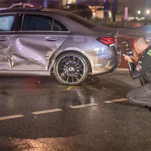Ein Polizist fotografiert den beschädigten Mercedes.